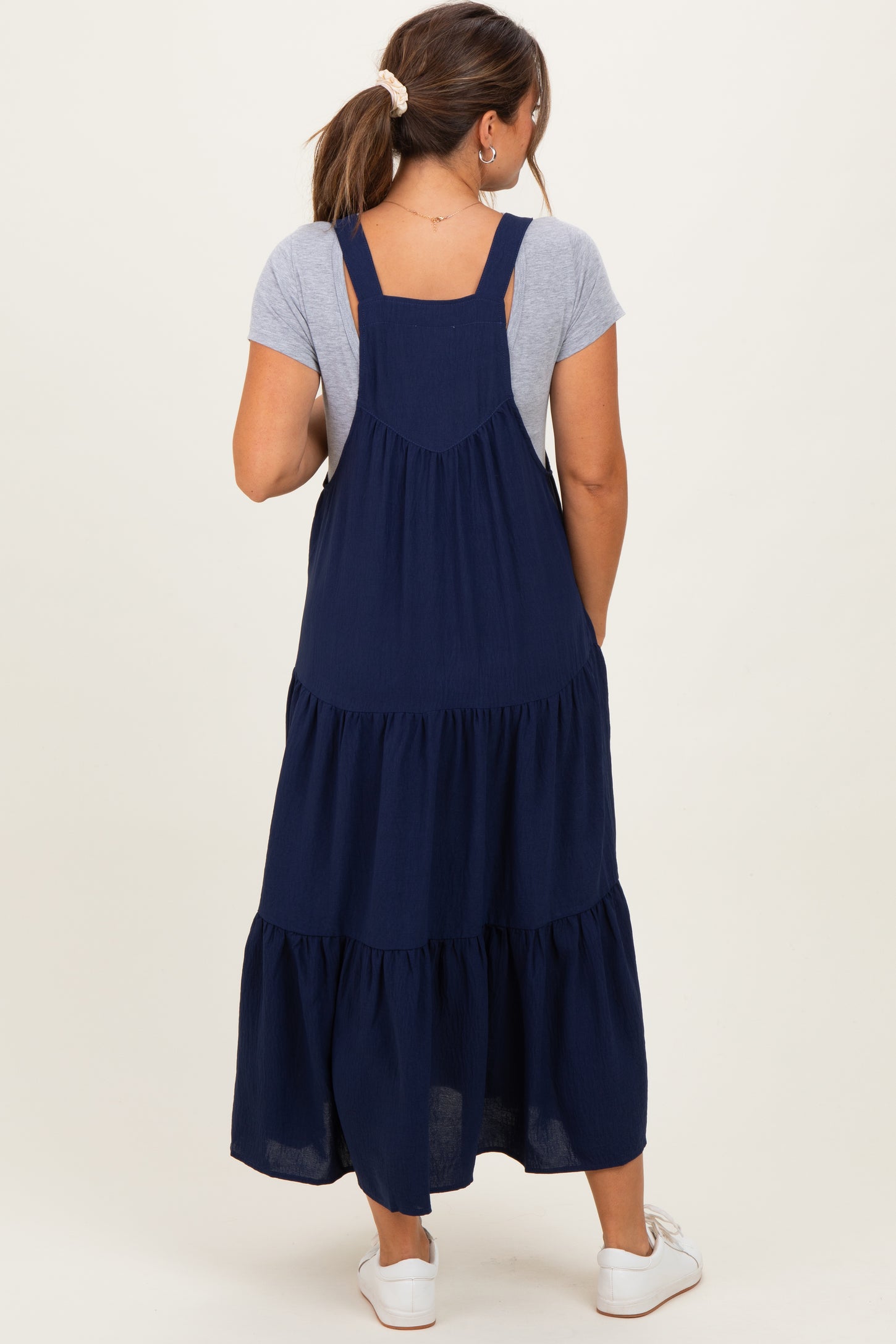woman wearing a navy blue maternity maxi dress with layered ruffles and a gray short sleeve top underneath