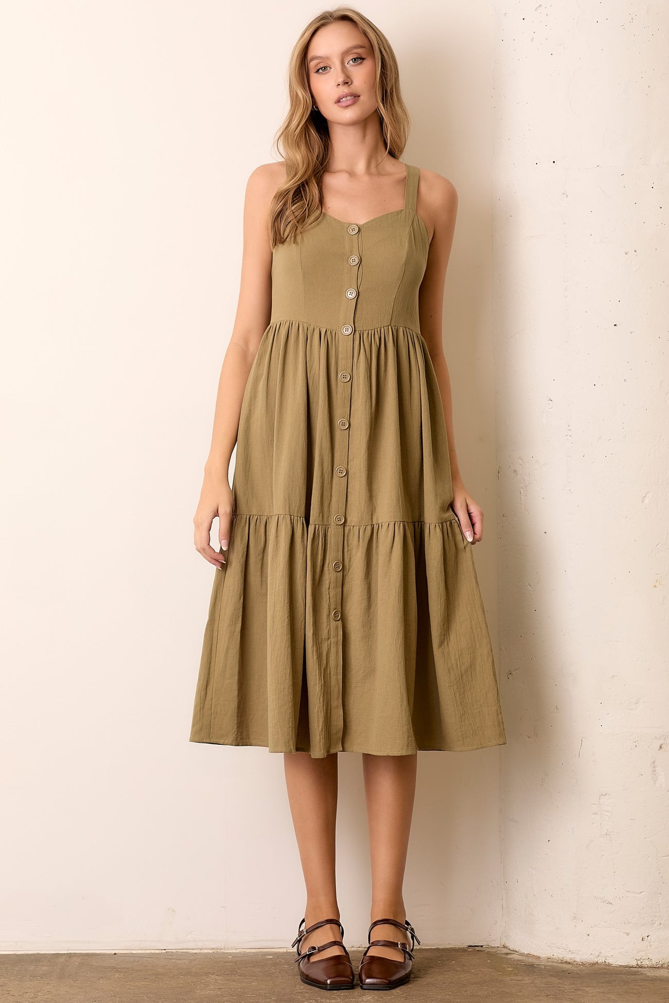 woman wearing an olive green button-up midi dress with a tiered skirt and adjustable straps