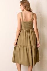 woman wearing an olive green midi dress with adjustable straps and smocked back detail, viewed from the back