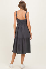 woman wearing a dark gray maternity dress with smocked bodice and tiered skirt, seen from the back