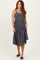 woman wearing a gray button-down midi dress with adjustable straps and a tiered skirt, posing with one hand on the fabric