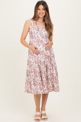 woman wearing a floral pink and white maternity dress with straps, showcasing her baby bump