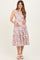 woman wearing a floral pink and white maternity dress with straps, showcasing her baby bump