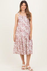 woman wearing a floral maternity midi dress with adjustable straps and a fitted bodice, showing her baby bump