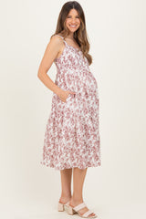 woman wearing a pink and white floral maternity dress with pockets and a visible baby bump