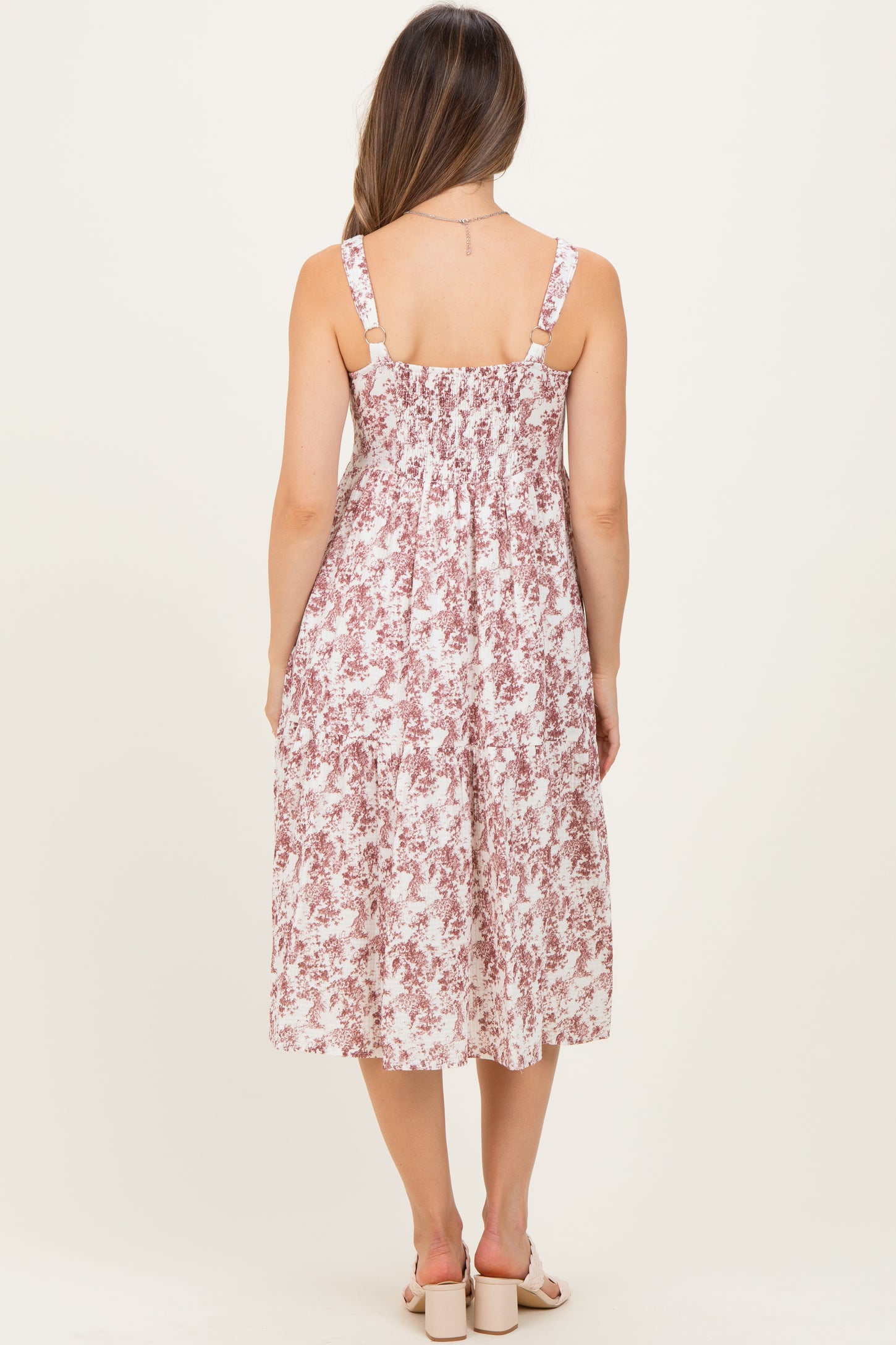 woman wearing a floral print maternity midi dress with adjustable straps and a smocked back, showing a baby bump