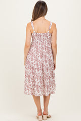 woman wearing a floral print maternity midi dress with adjustable straps and a smocked back, showing a baby bump