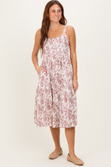 woman wearing a floral midi dress with a button front and pockets, styled with a relaxed fit and thin straps