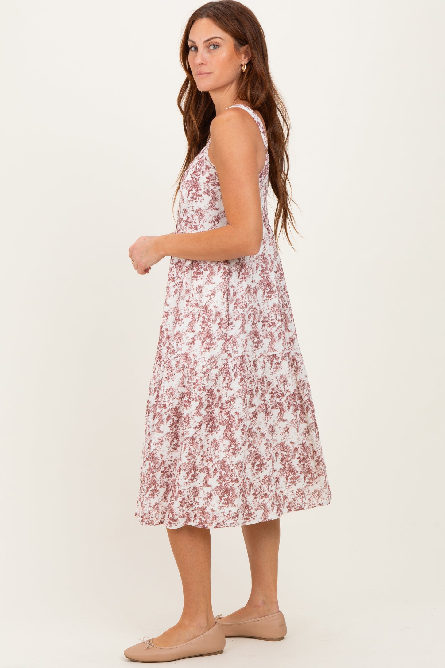 woman wearing a pink and white floral midi dress with adjustable straps and a flowy silhouette