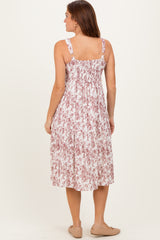 woman wearing a back view of a pink and white floral midi dress with adjustable straps and smocked bodice