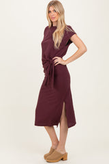 woman wearing a maroon midi dress with a side tie detail and slits, styled with beige clogs