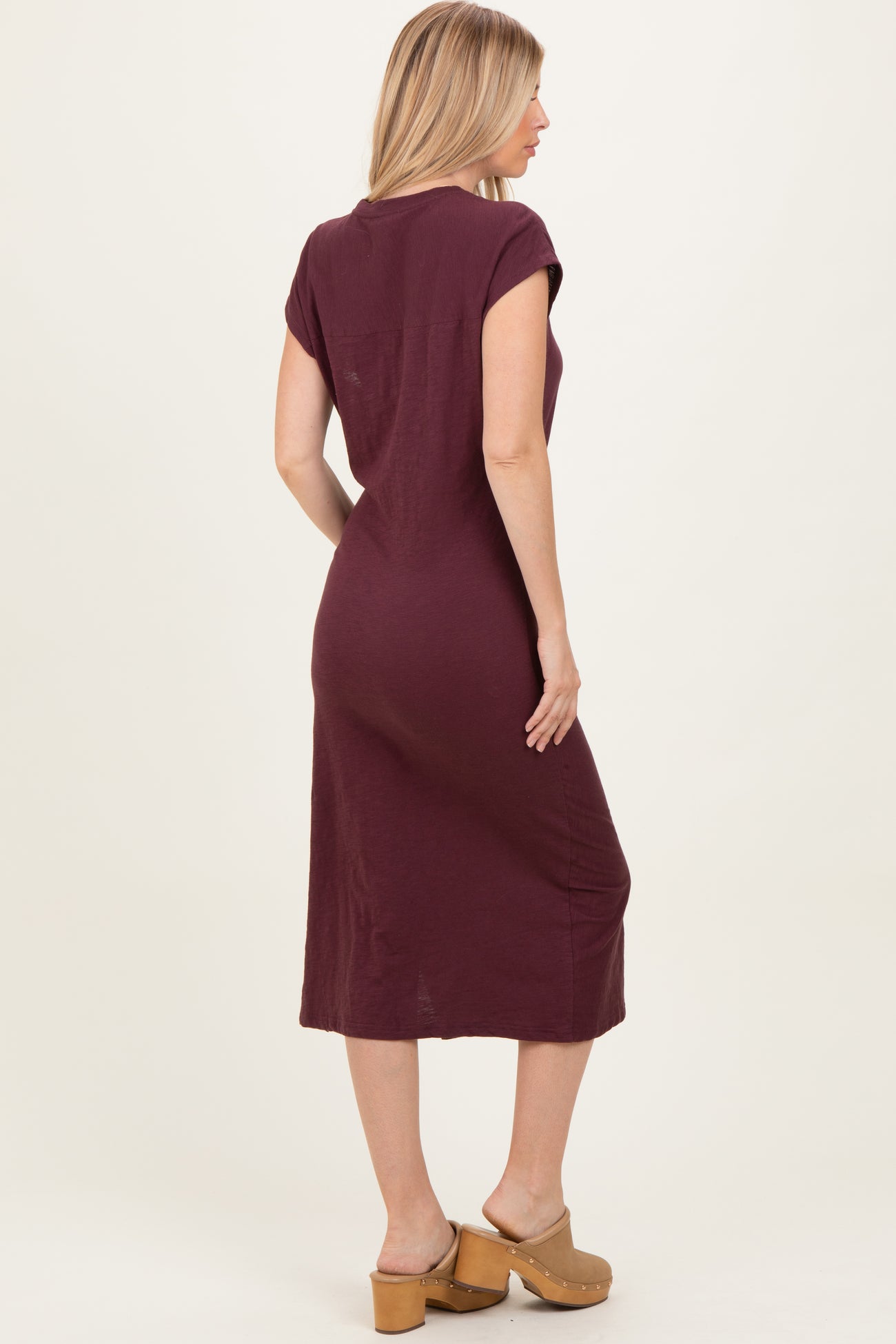woman wearing a maroon short sleeve midi dress, shown from the back, paired with tan platform sandals