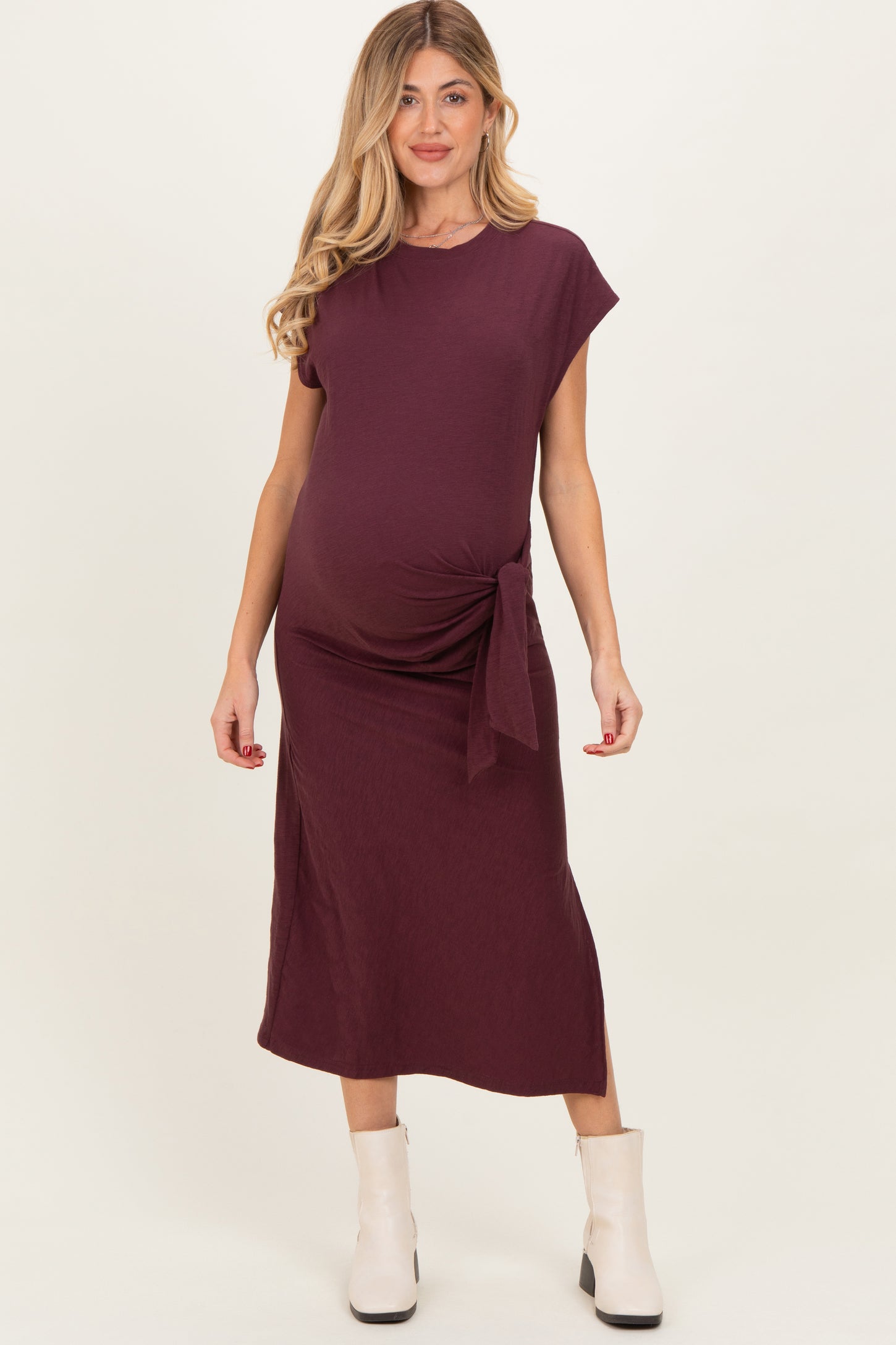 woman wearing a burgundy maternity dress with a side tie detail and a visible baby bump