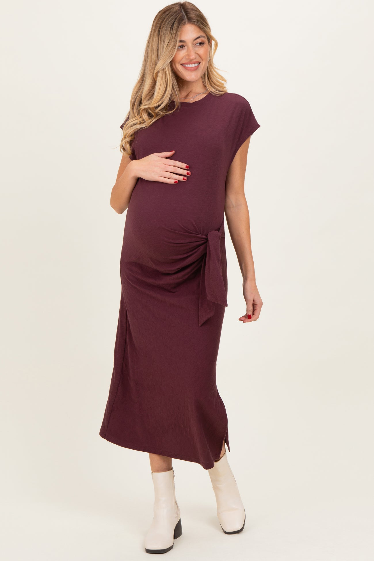 woman wearing a burgundy maternity dress with a side tie detail and showing her baby bump