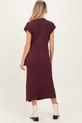 woman wearing a burgundy maternity dress with short sleeves, showing the back view and paired with ankle boots