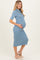 woman wearing a light blue fitted maternity dress, highlighting her baby bump, styled with short sleeves and a mock neck