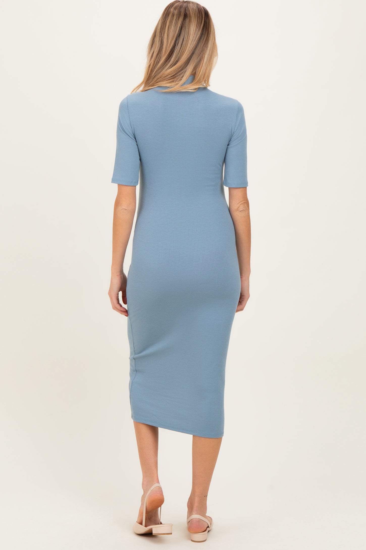 woman wearing a light blue ribbed maternity midi dress with short sleeves and a fitted silhouette