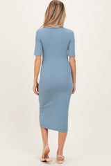 woman wearing a light blue ribbed maternity midi dress with short sleeves and a fitted silhouette