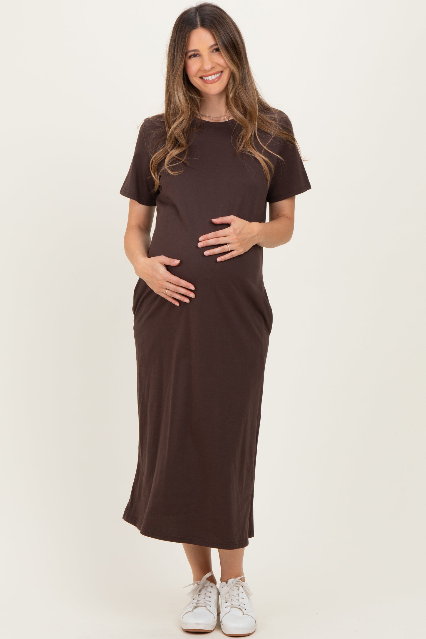 woman wearing a dark brown short sleeve maternity dress and holding her baby bump