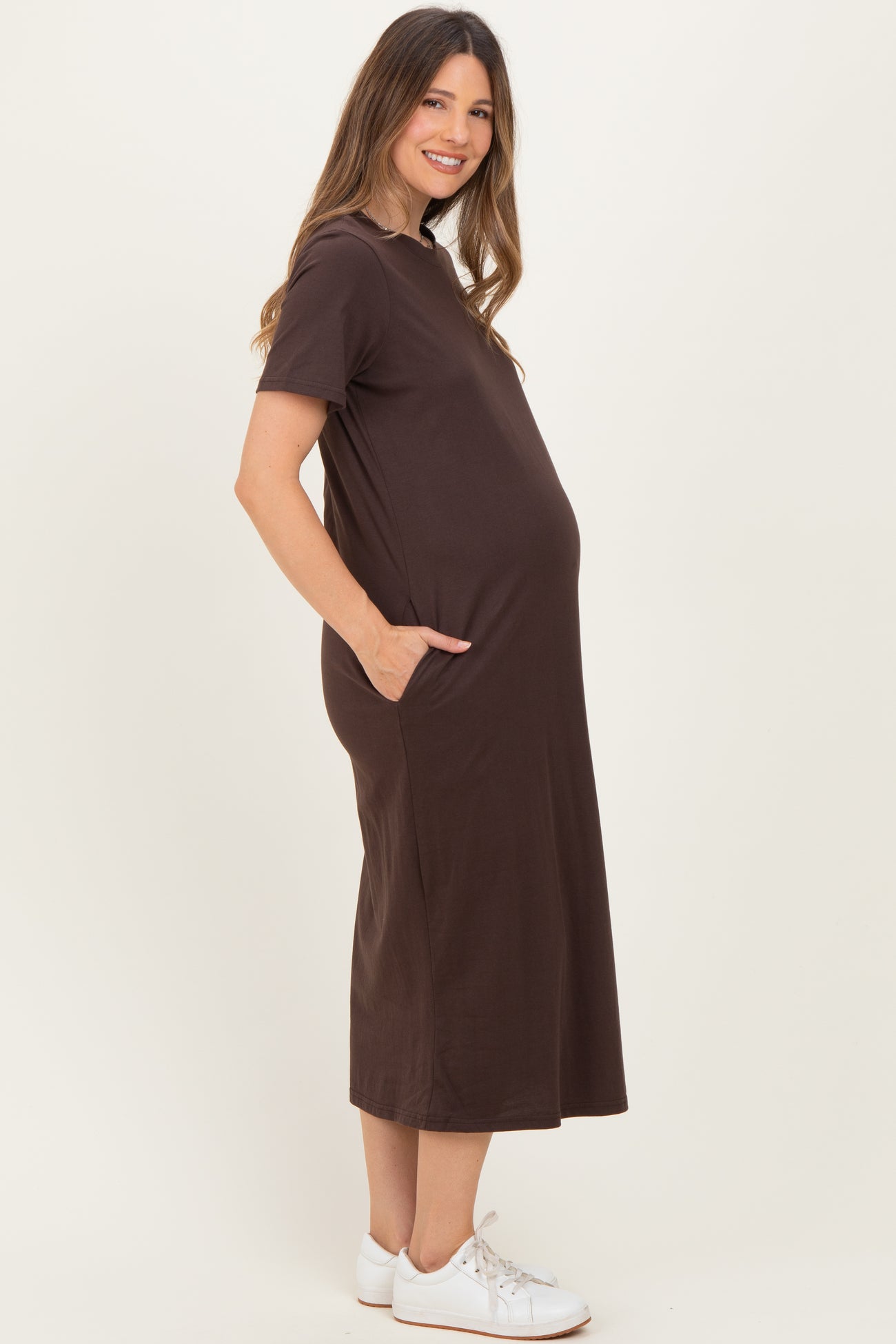 woman wearing a brown short sleeve maternity dress with pockets and a visible baby bump