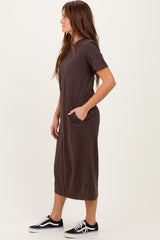 woman wearing a dark brown short sleeve maxi dress with side pockets and styled with black sneakers