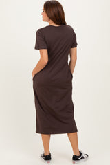 woman wearing a brown short sleeve maxi dress with pockets, standing with her back to the camera