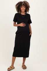 woman wearing a black short sleeve maternity dress with pockets and holding her baby bump