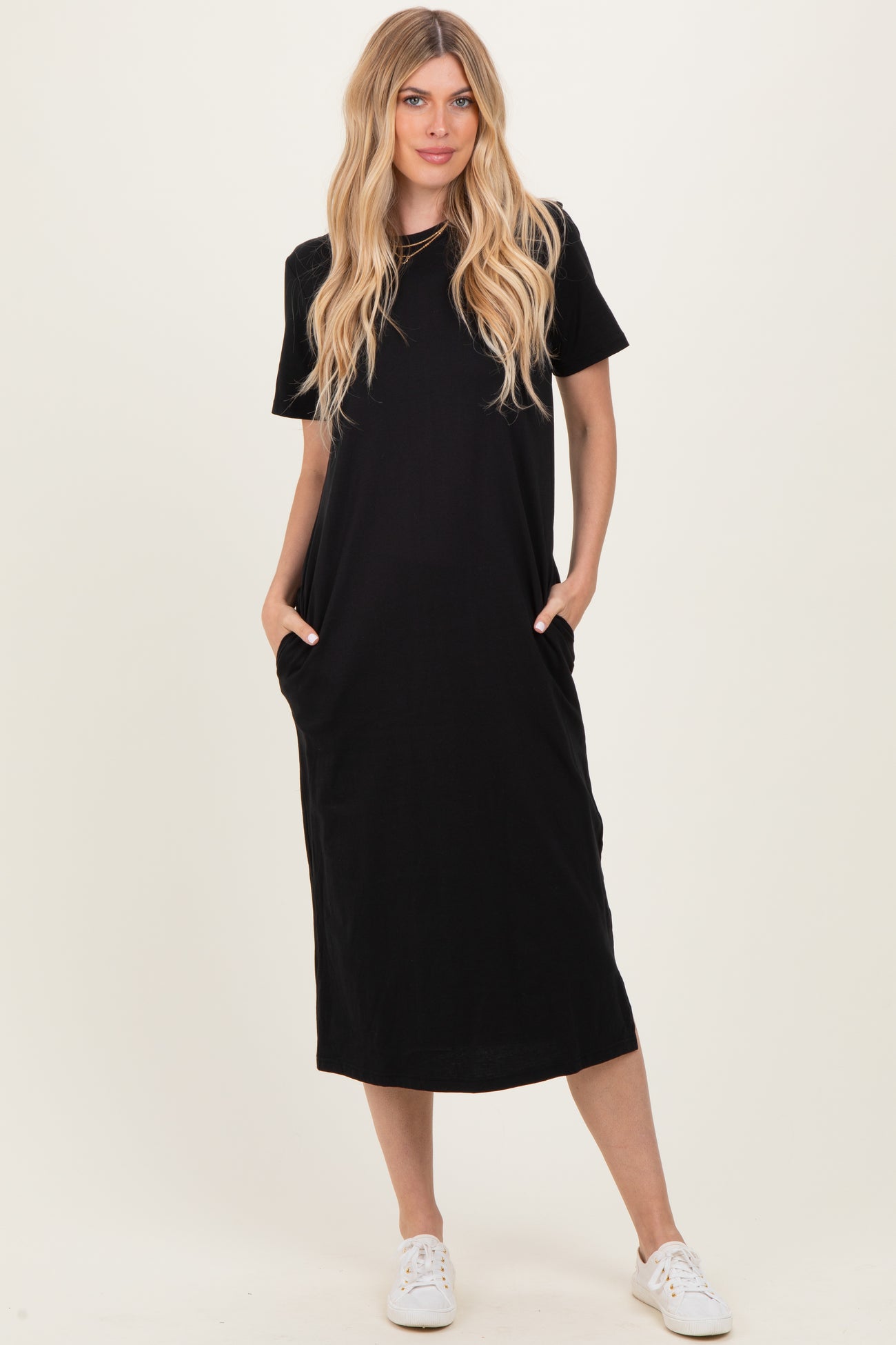 woman wearing a black short sleeve maxi dress with side pockets and white sneakers