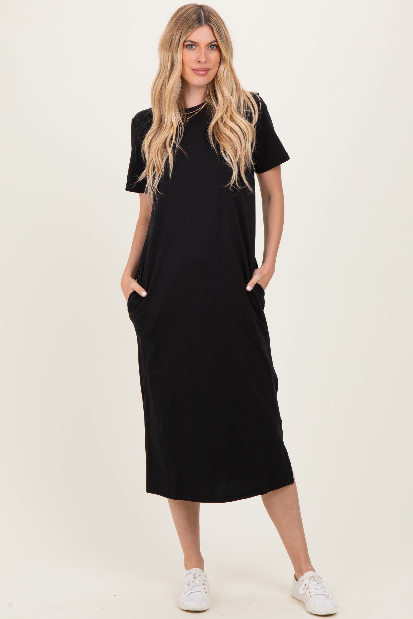woman wearing a black short sleeve maxi dress with side pockets and white sneakers