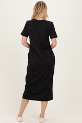 woman wearing a black short sleeve midi dress, seen from the back, with a relaxed fit and side pockets