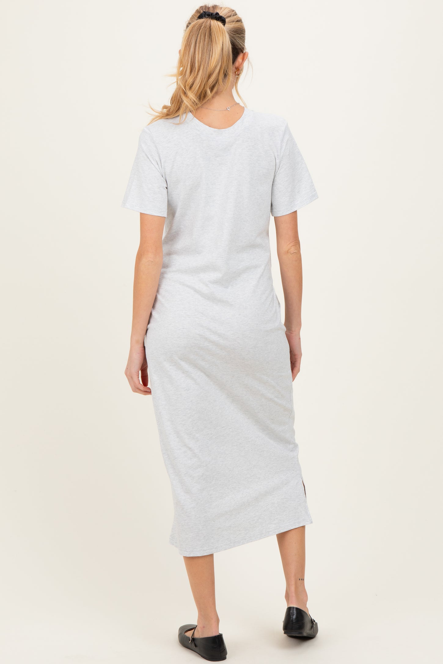 woman wearing a gray short sleeve maternity dress with a side slit, shown from the back