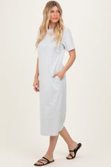 woman wearing a light gray short sleeve maxi dress with pockets and black strappy sandals
