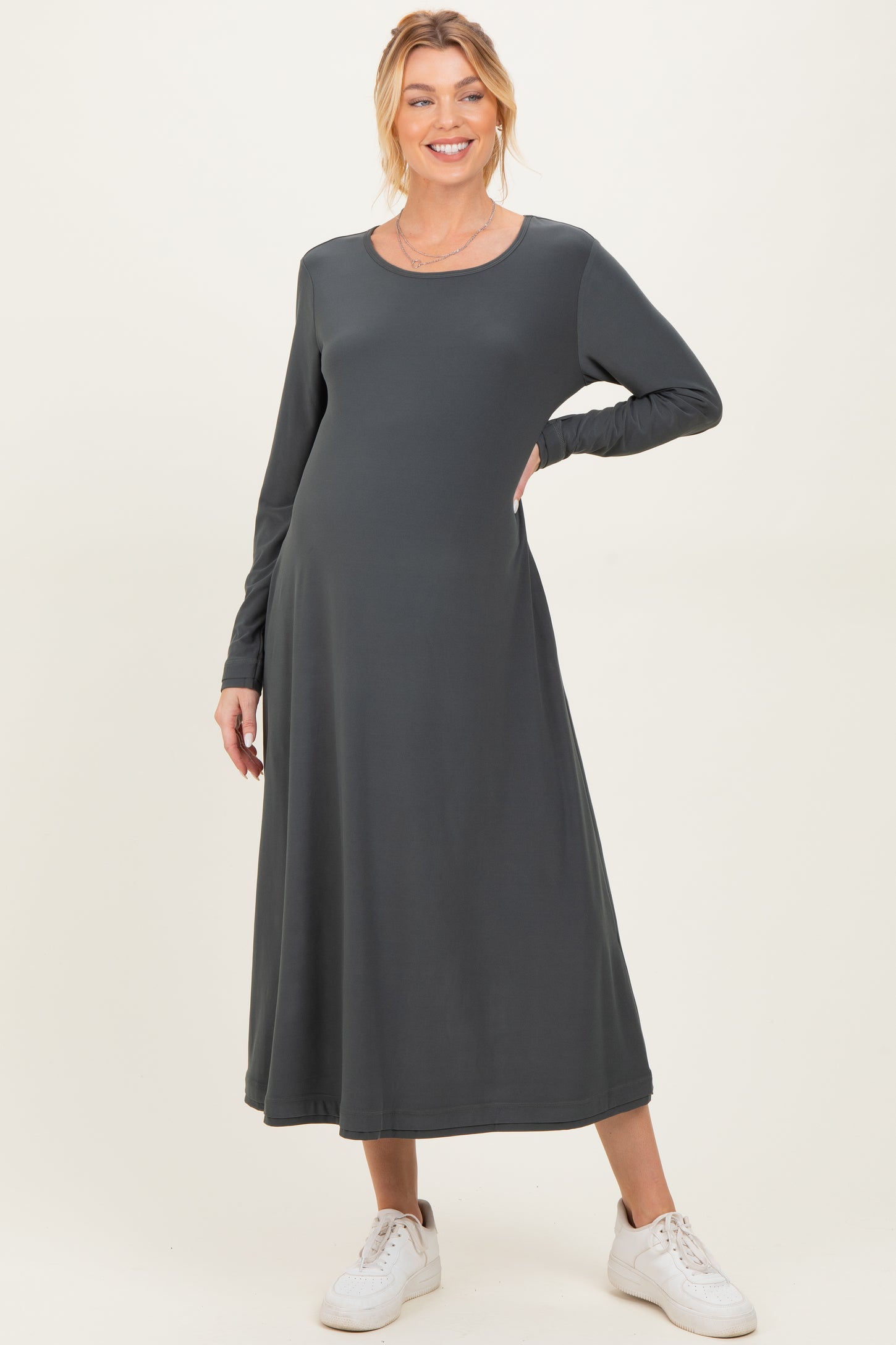 woman wearing a dark gray long sleeve maternity dress with a flowy skirt and a visible baby bump