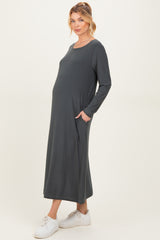 woman wearing a dark gray long sleeve maternity dress with pockets and a visible baby bump
