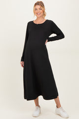 woman wearing a black long sleeve maternity dress with a relaxed fit and visible baby bump