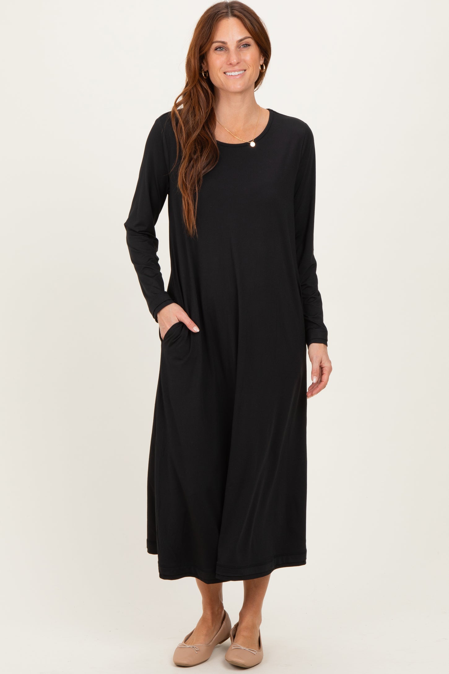 woman wearing a black long sleeve maxi dress with a round neckline and side pockets