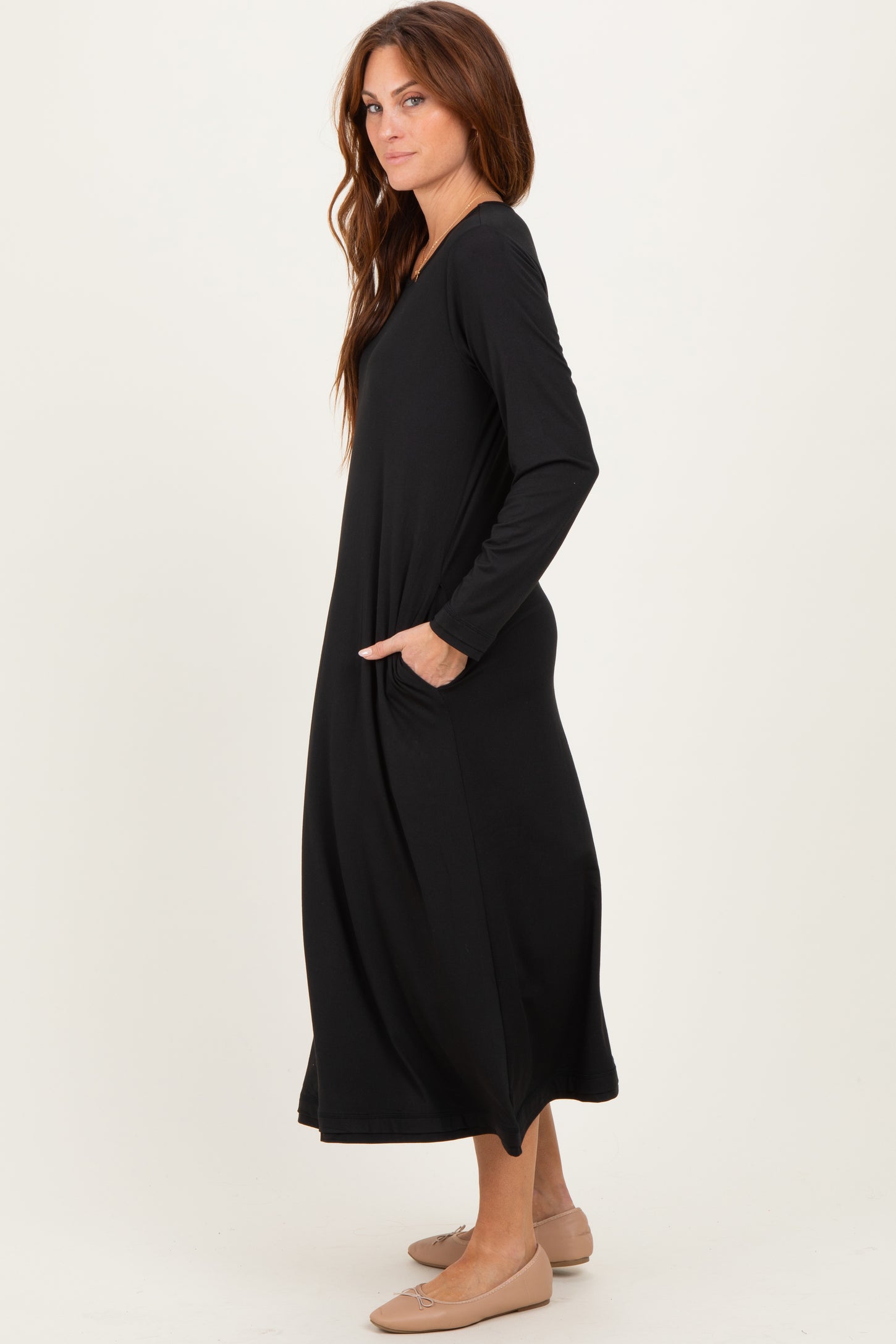 woman wearing a black long sleeve maxi dress with side pockets and a relaxed fit