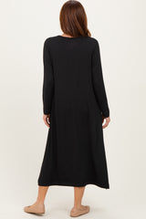 woman wearing a black long sleeve maxi dress, viewed from the back, with tan slip-on shoes