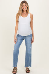 woman wearing a white ribbed maternity tank top and light blue distressed maternity jeans, showing her baby bump