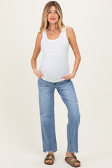 woman wearing a white ribbed maternity tank top and light blue distressed jeans, showing her baby bump