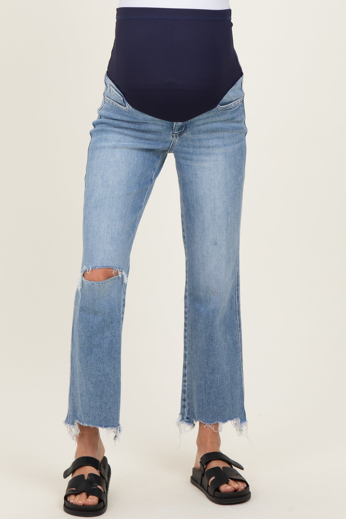 woman wearing a pair of distressed light blue maternity jeans with a dark blue over-the-bump waistband