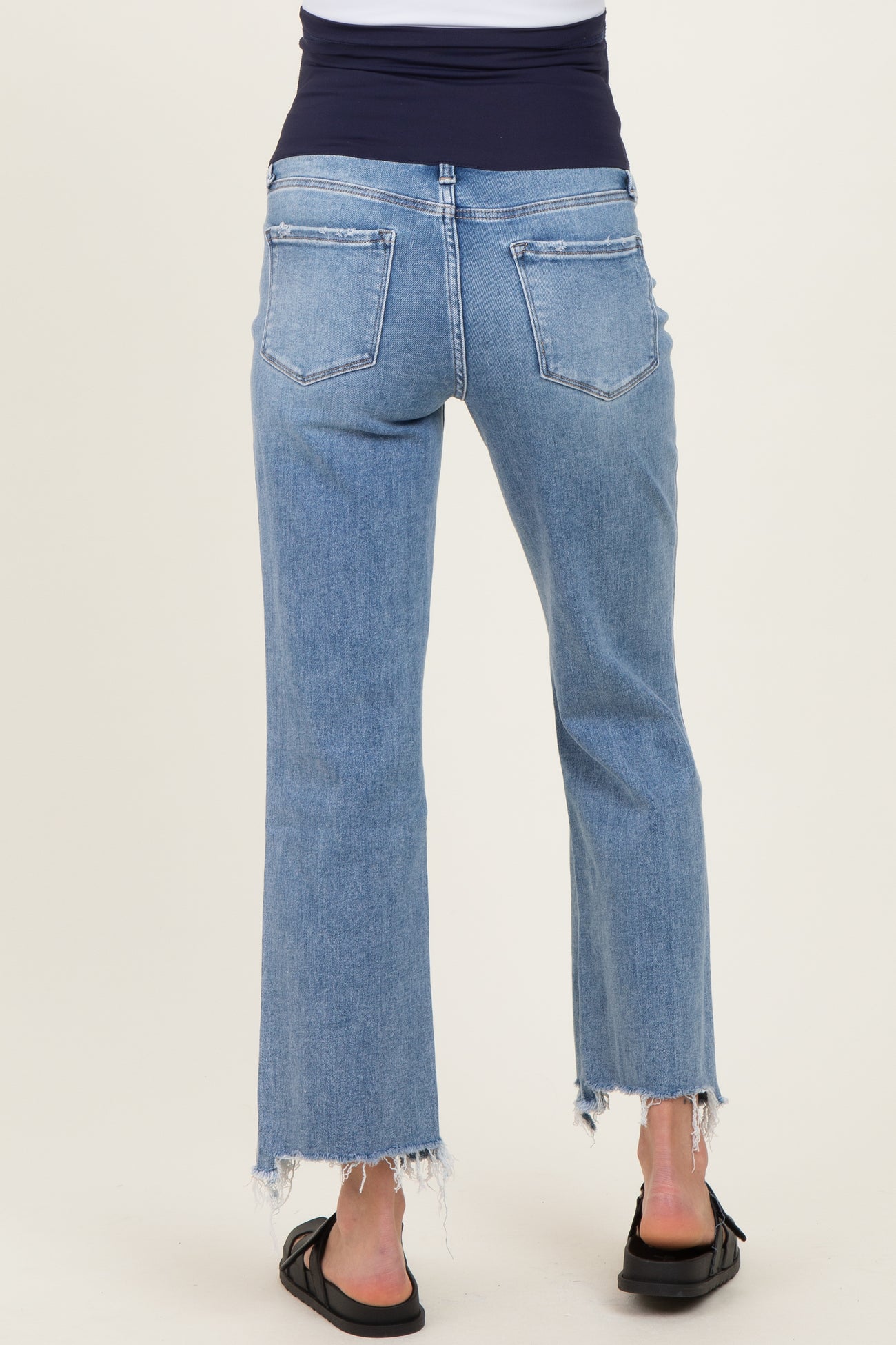 woman wearing light blue maternity jeans with a frayed hem, viewed from the back
