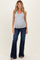 woman wearing a gray sleeveless maternity top and dark blue flared jeans, showing her baby bump