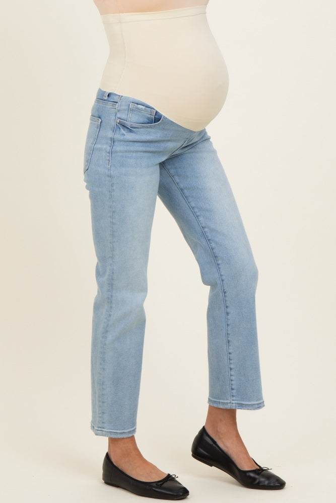 woman wearing light blue maternity jeans with a supportive belly panel and black ballet flats, showing her baby bump