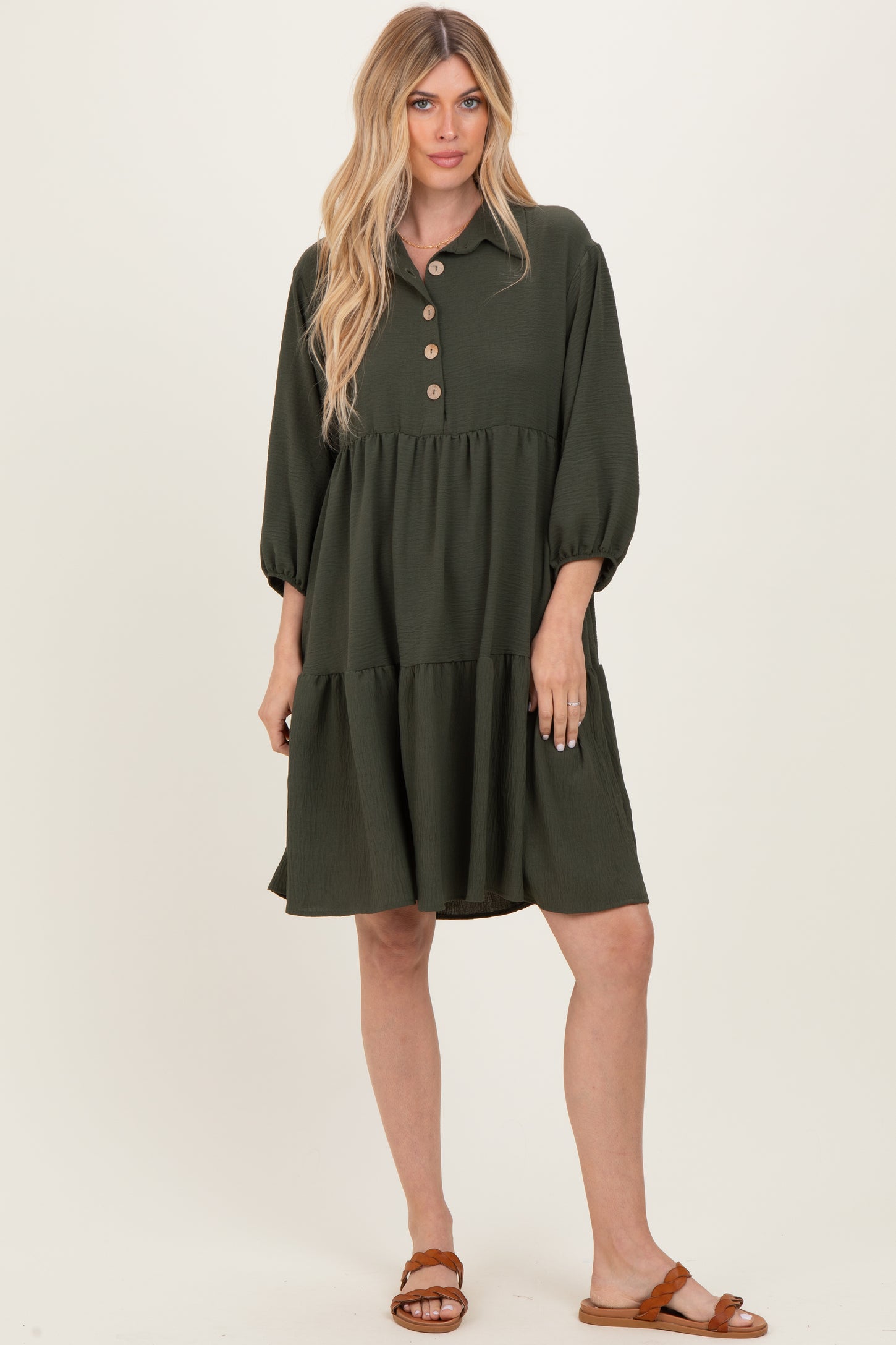 woman wearing an olive green button-up tiered dress with long sleeves and a relaxed fit