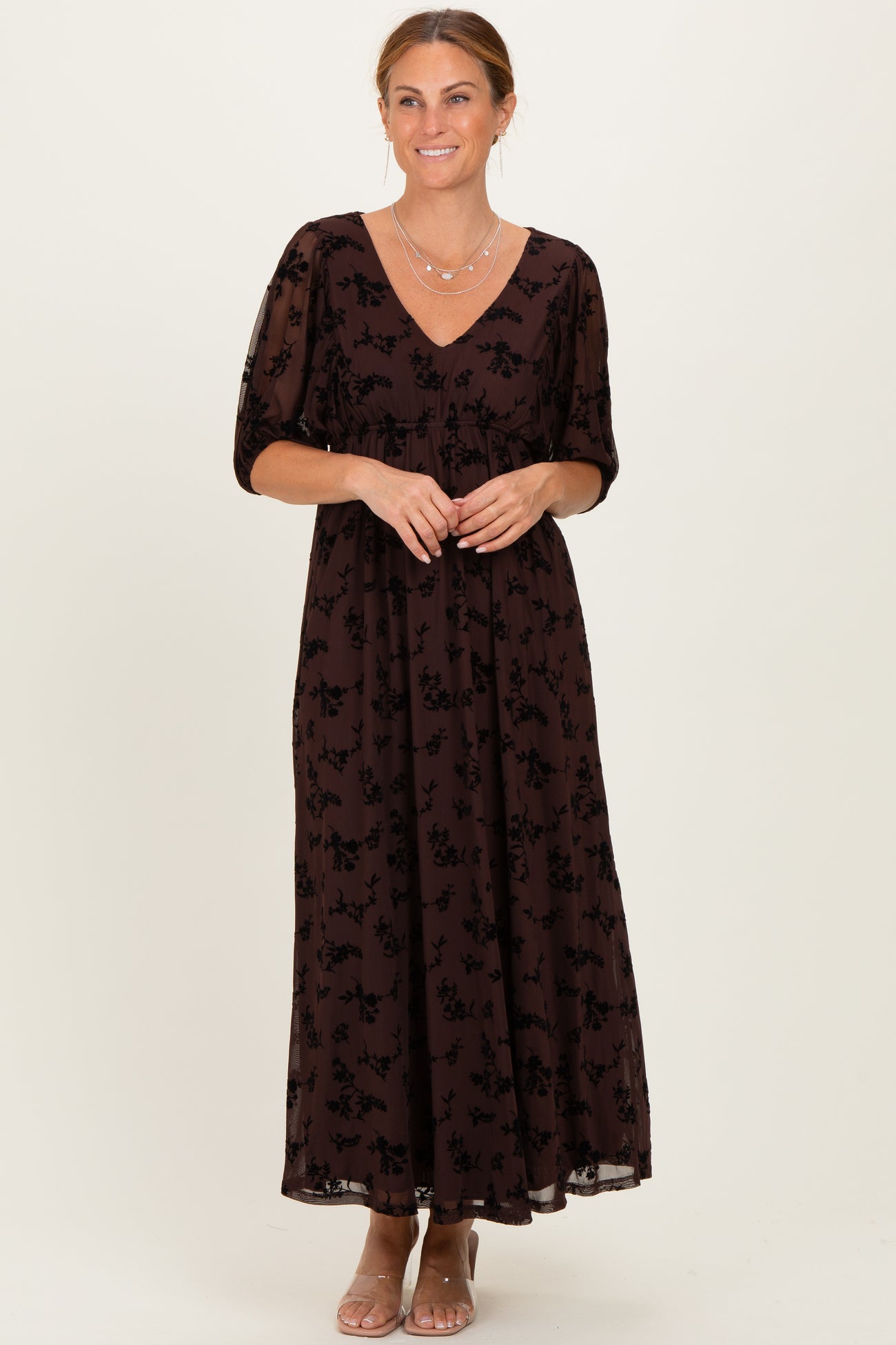 woman wearing a brown maxi dress with a floral print and short puff sleeves