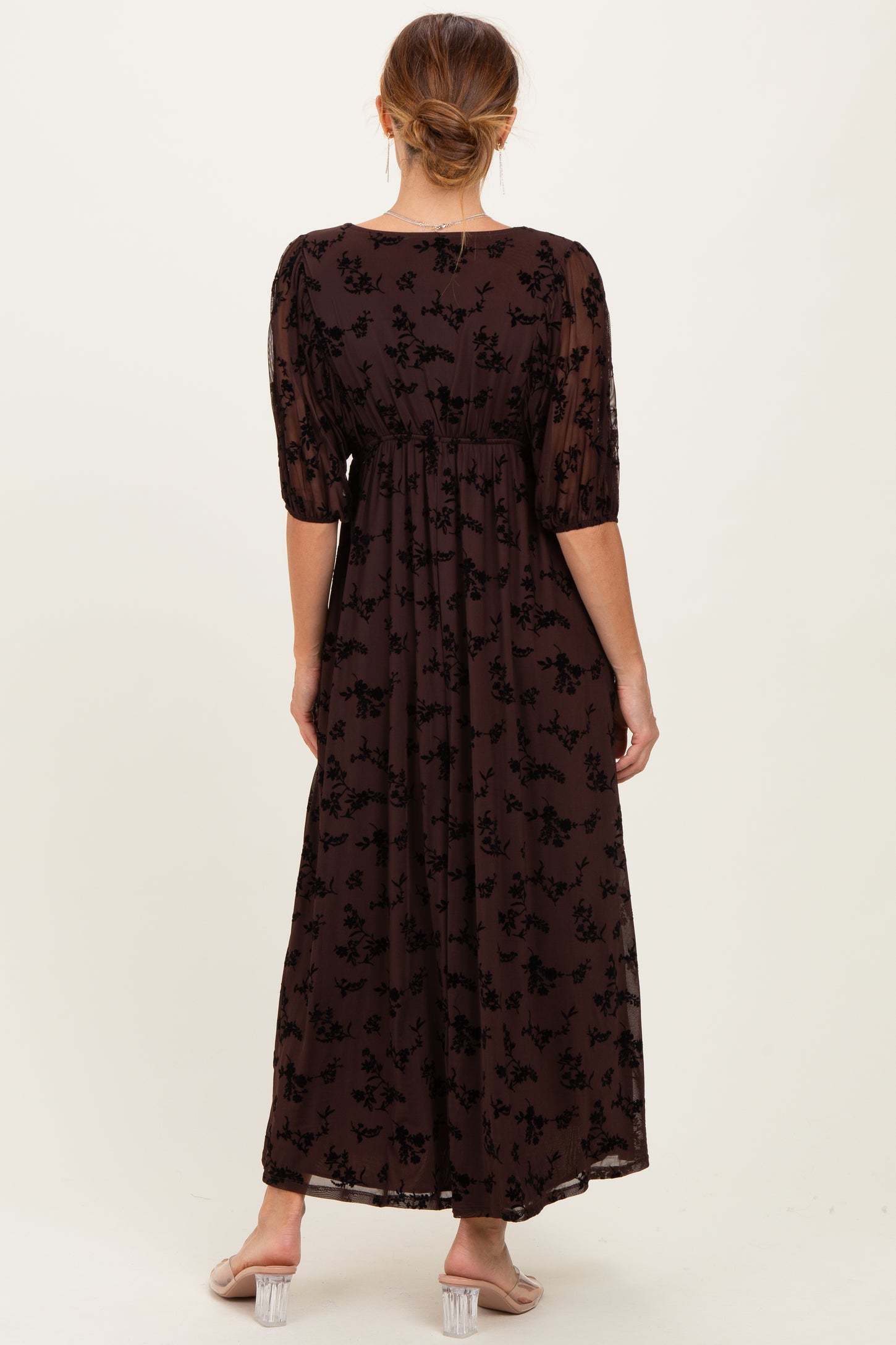 woman wearing a brown floral maxi dress with puff sleeves, viewed from the back