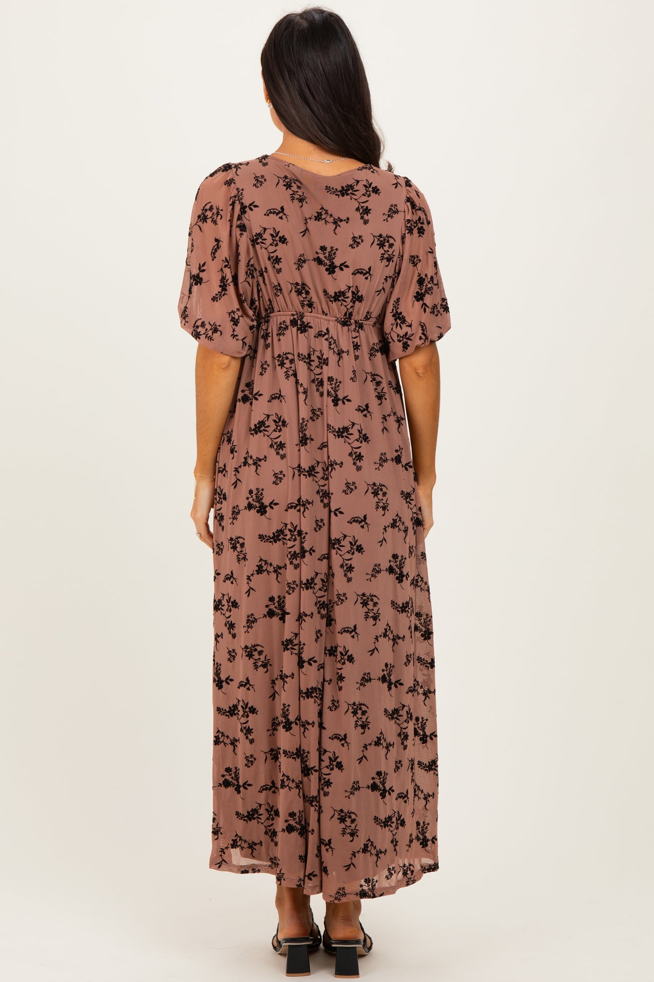 woman wearing a brown floral maxi dress with short puff sleeves, shown from the back