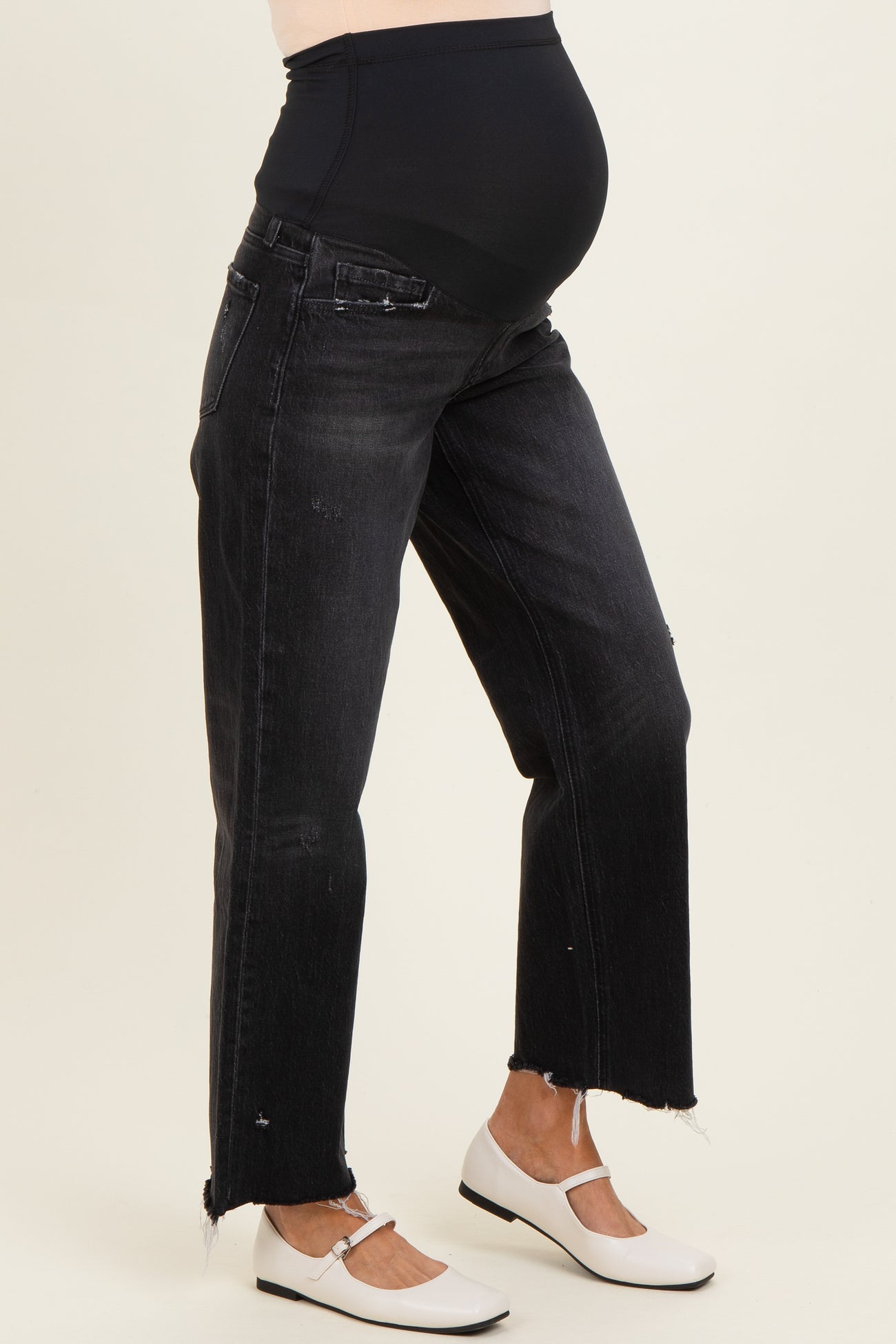 woman wearing black maternity jeans with a stretchy waistband and frayed hem, showing her baby bump