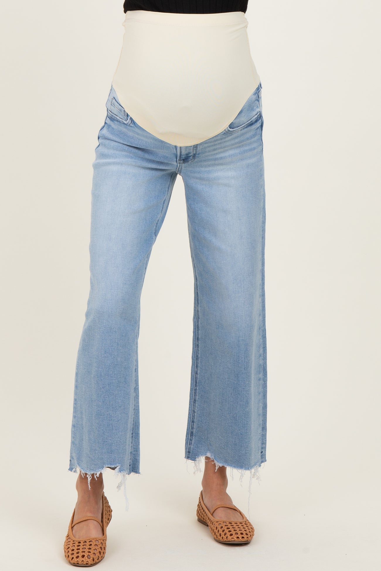 maternity wear light wash flared jeans with a cream colored over-the-bump panel and distressed hem